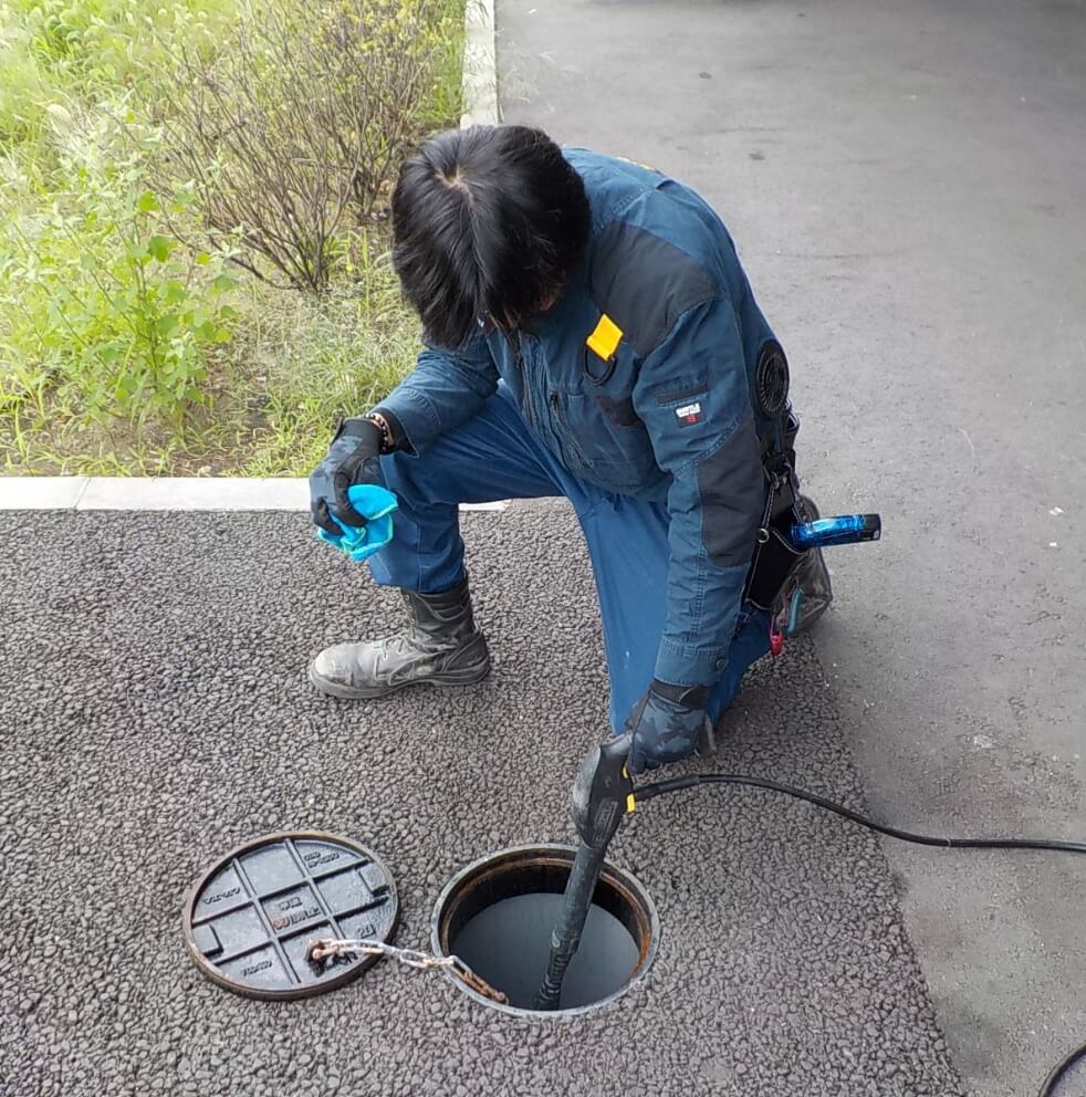 雨水マスを清掃する設備管理部 青山敬志さん